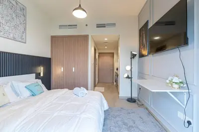 a bedroom with a large white bed and a television at Cozy studio in Azizi Riviera with beautiful views in Dubai