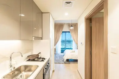 a small kitchen with a sink and a bed in a room at Cozy studio in Azizi Riviera with beautiful views in Dubai