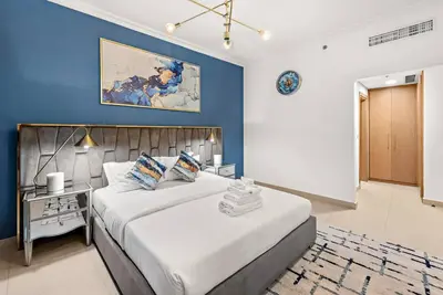 a bedroom with a large bed and a blue wall at Luxury 2BR Burj View with Pool Walk to Mall & Metro Dining Shopping in Dubai