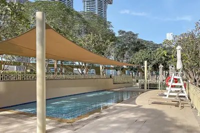 a swimming pool with a tan umbrella and a ladder at Luxury 2BR Burj View with Pool Walk to Mall & Metro Dining Shopping in Dubai