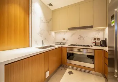 a kitchen with wooden cabinets and a stove top oven at NewArabian Opera Address Residences in Dubai
