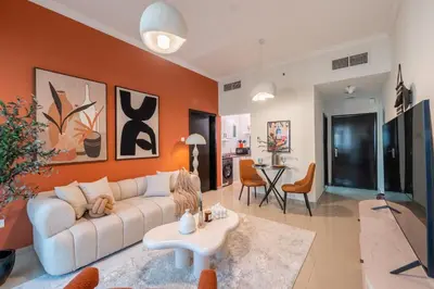 a living room with a white couch and an orange wall at Stylish 1BR Apartment! Near Metro & Stroll to Dubai Marina in Dubai