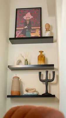 a shelf with a painting of a woman in a hat at Stylish 1BR Apartment! Near Metro & Stroll to Dubai Marina in Dubai