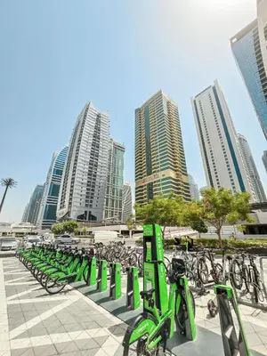 a row of green bikes parked in front of tall buildings at Stylish 1BR Apartment! Near Metro & Stroll to Dubai Marina in Dubai