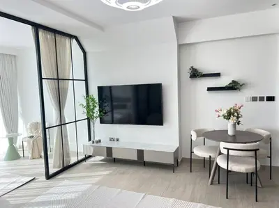 a white living room with a table and a tv at Studio apartment MeDoRe Tower in Dubai