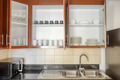 a kitchen with a sink and cupboards filled with dishes at Blueground Sadaf sea view elevator gym DXB-925 in Dubai
