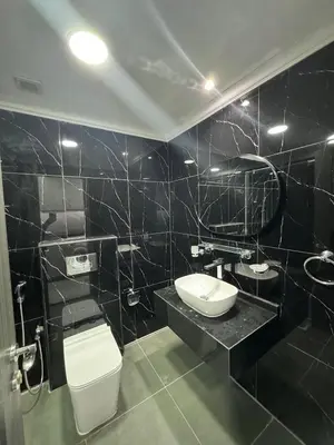 a black tiled bathroom with a toilet and a sink at Jvc diamond 1 home in Dubai