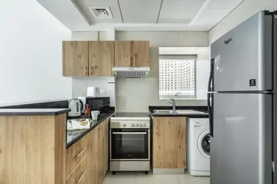 a kitchen with wooden cabinets and a white refrigerator at ShoresInn - Mesmerizing Waterfront in Dubai Marina in Dubai