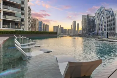 a swimming pool with white chairs in a city at Waves - Stylish 13th-Floor Studio with Top-Notch Amenities in Dubai