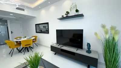a living room with a tv and a table and chairs at Dubai Marina - 1 BHK Classy Apartment in Dubai