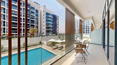 an apartment balcony with a swimming pool and views of buildings at Azizi Riviera 18 - Neat One Bedroom in Meydan in Dubai