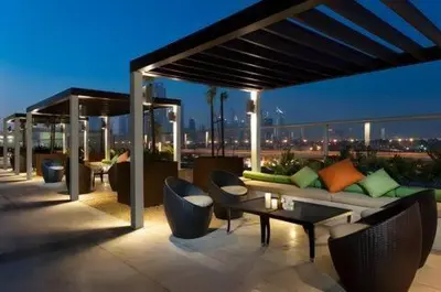 a rooftop patio with a couch and tables and chairs at Luxurious Apartment 500 Meters Next to Dubai Mall in Dubai