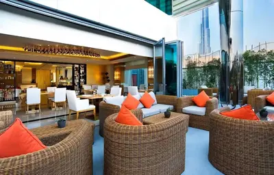 a restaurant with wicker chairs and tables with orange pillows at Luxurious Apartment 500 Meters Next to Dubai Mall in Dubai