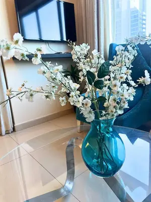 a blue vase with flowers sitting on a glass table at Luxurious Apartment 500 Meters Next to Dubai Mall in Dubai