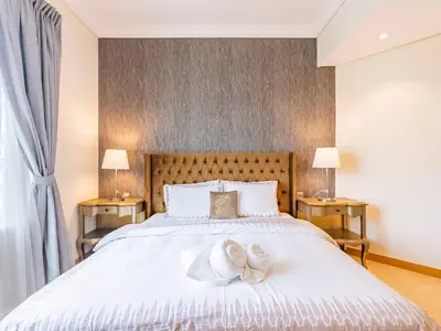 a bedroom with a large white bed with two shoes on it at Chic 4BR Apt Pool Palm Beach Club Dubai in Dubai