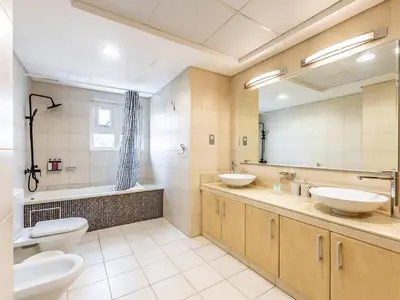 a bathroom with two sinks and a large mirror at Chic 4BR Apt Pool Palm Beach Club Dubai in Dubai