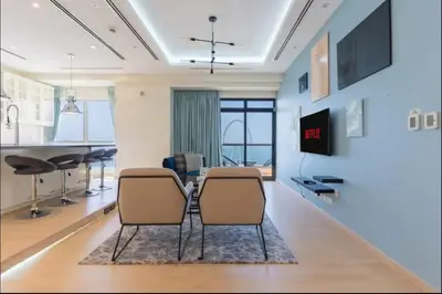 a living room with two chairs and a tv at AWS Holiday Homes - Spectacular Sea Views in Dubai