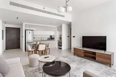 a white living room with a tv and a table at Silkhaus 1BDR with Beach Access in Marina Vista in Dubai