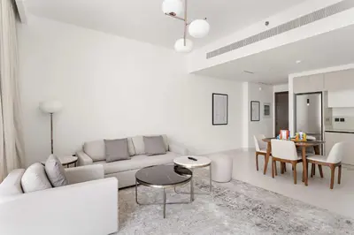 a white living room with a couch and a table at Silkhaus 1BDR with Beach Access in Marina Vista in Dubai
