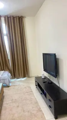 a living room with a flat screen tv on a table at Furnished Apartment in Silicon Oasis on Prime Location in Dubai