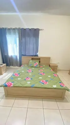 a bed with a green comforter with flowers on it at Furnished Apartment in Silicon Oasis on Prime Location in Dubai