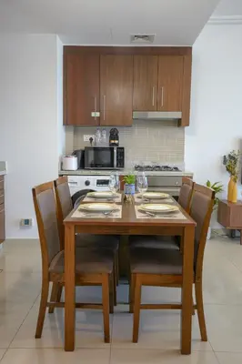 a kitchen with a wooden table with chairs and a microwave at CH Urban Haven - 1BR at Boulevard Point with Burj & Fountain Views in Dubai