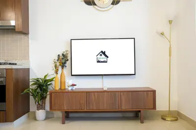 a living room with a tv on a wall at CH Urban Haven - 1BR at Boulevard Point with Burj & Fountain Views in Dubai