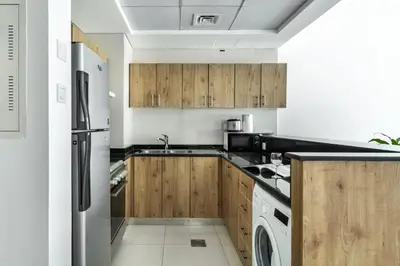 a kitchen with wooden cabinets and a stainless steel refrigerator at ShoresInn - Artistic Retreat in Dubai Marina in Dubai