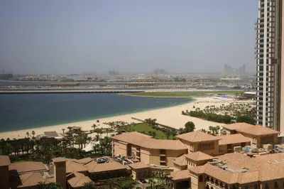 a view of a beach with a building and the ocean at Cozy 2 Bedroom at JBR Beachfront With Pool And Gym in Dubai