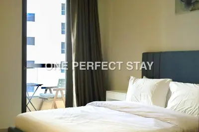 a bedroom with a bed with white sheets and a window at Cozy 2 Bedroom at JBR Beachfront With Pool And Gym in Dubai