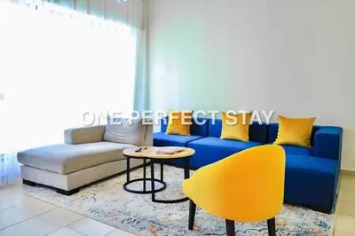 a living room with a blue couch and a yellow chair at Cozy 2 Bedroom at JBR Beachfront With Pool And Gym in Dubai