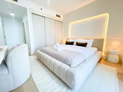 a white bedroom with a large bed and a chair at Stunning 2BR In Dubai Marina With Amazing views in Dubai
