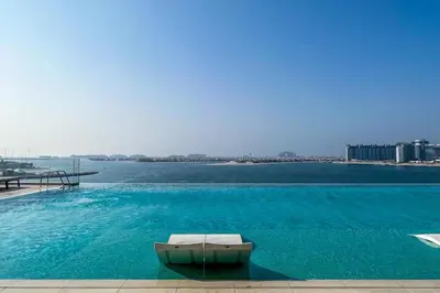 a large swimming pool with a couch in front of the water at Luxury Living with Private Beach in Dubai