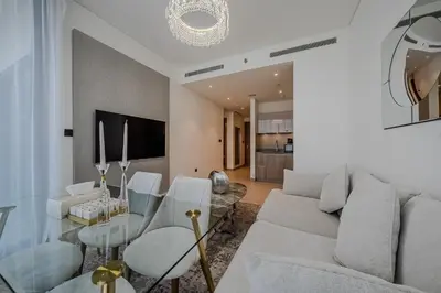a living room with a couch and a glass table at Stylish 1 BDR apartment in Sobha Waves in Dubai