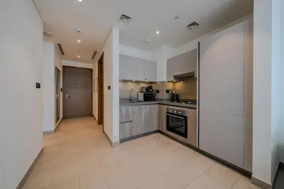 a kitchen with white walls and stainless steel appliances at Stylish 1 BDR apartment in Sobha Waves in Dubai