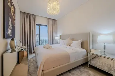 a bedroom with a large bed and a chandelier at Stylish 1 BDR apartment in Sobha Waves in Dubai