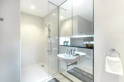 a white bathroom with a sink and a shower at Blueground DIFC pool gym DXB-468 in Dubai