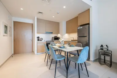 a kitchen and dining room with a table and chairs at Exquisite 1BDR apartment in Creek with Pool View in Dubai