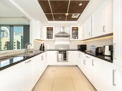 a kitchen with white cabinets and a large window at Lavish 2 Bedroom I Burj Khalifa & Fountain Views I Free Gym, Pool, Parking, Wi-Fi and PS5 I by Skyline Serenity in Dubai