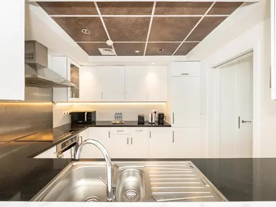 a kitchen with white cabinets and a sink at Lavish 2 Bedroom I Burj Khalifa & Fountain Views I Free Gym, Pool, Parking, Wi-Fi and PS5 I by Skyline Serenity in Dubai