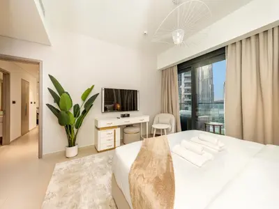 a white bedroom with a large bed and a tv at Skyline 2 Bedroom Apartment I Burj Khalifa & Fountain Views I Free Gym, Pool, Parking, Wi-Fi and PS5 in Dubai