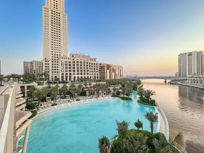 a large swimming pool next to a river with buildings at Chic 2BR Vida Stay, Creek Views & Prime Location Near Attractions in Dubai