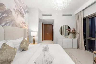a white bedroom with a large bed and a mirror at Chic 2BR Vida Stay, Creek Views & Prime Location Near Attractions in Dubai