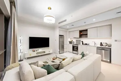 a living room with a white couch and a kitchen at Chic 2BR Vida Stay, Creek Views & Prime Location Near Attractions in Dubai