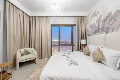 a bedroom with a large white bed and a chair at Chic 2BR Vida Stay, Creek Views & Prime Location Near Attractions in Dubai