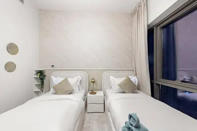 two white beds in a room with a window at Chic 2BR Vida Stay, Creek Views & Prime Location Near Attractions in Dubai