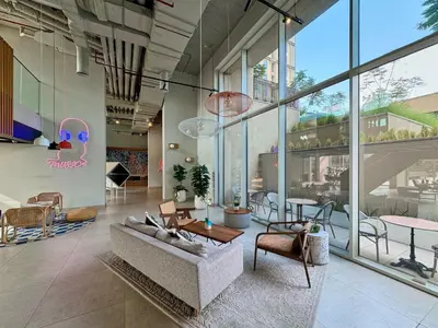 a living room with a couch and tables and windows at Colorful1BR Apartment in Dubai Hills Next to Mall in Dubai