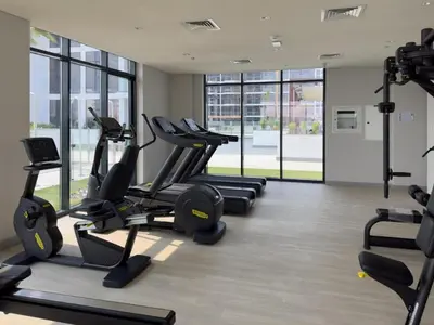 a gym with treadmills and ellipticals in a room with windows at Bright Studio in Azizi Riviera Perfect Getaway in Dubai