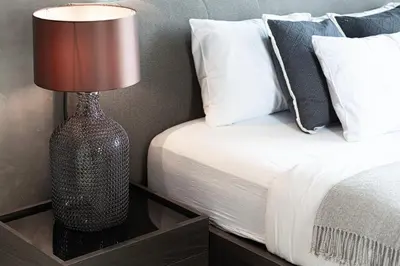 a lamp sitting on a night stand next to a bed at 2BR Steps from JBR Beach in Dubai