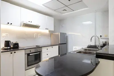 a kitchen with white cabinets and a black counter top at 2BR Steps from JBR Beach in Dubai